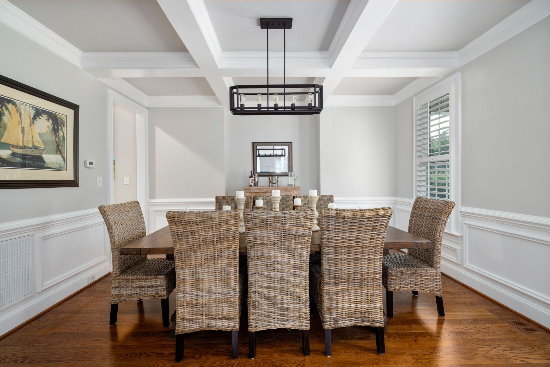 A beautifully designed dining room featuring wicker chairs, a wooden table, and minimalist decor.