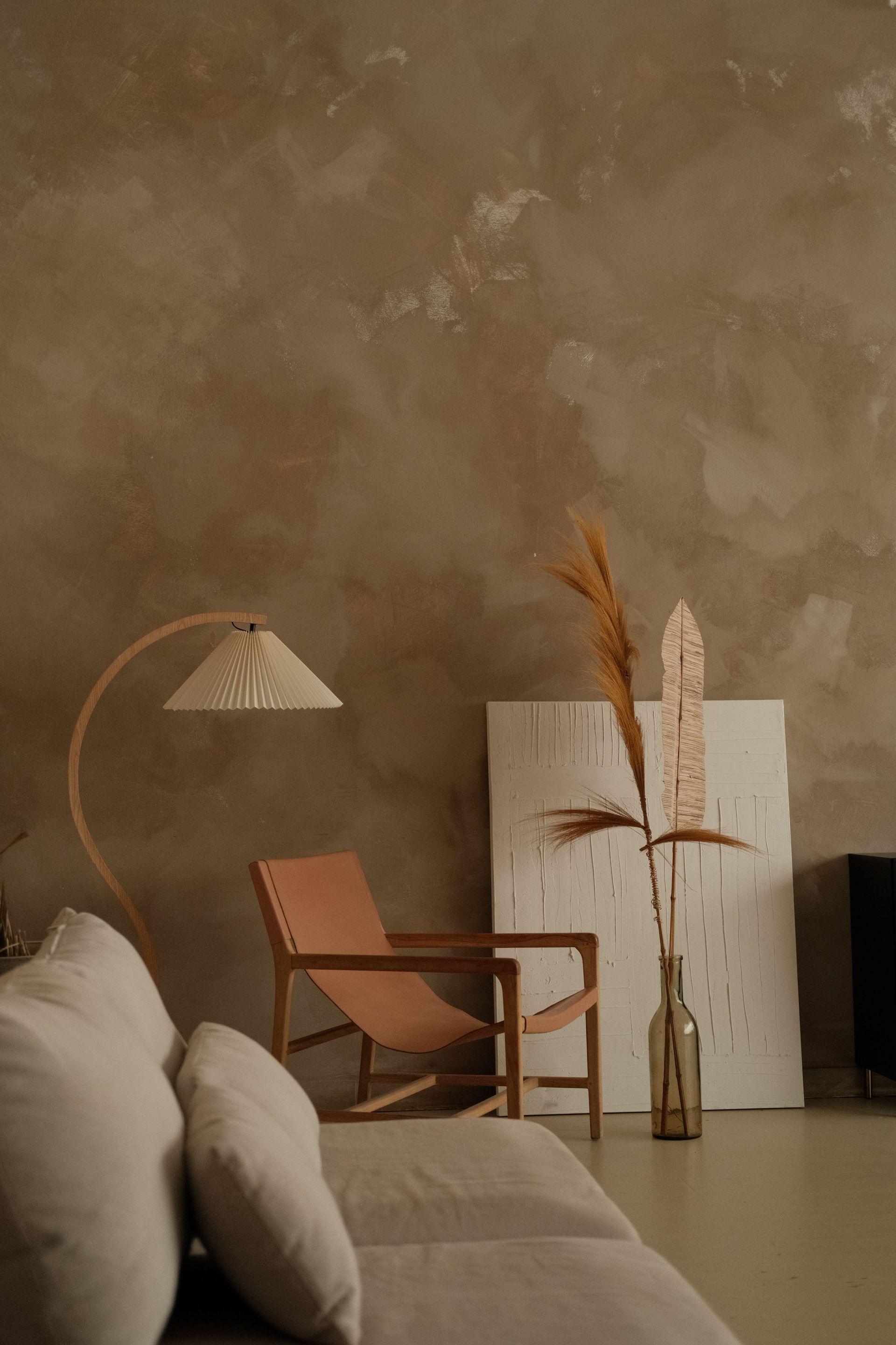 Elegant minimalist interior featuring boho decor, a leather chair, and textured walls.